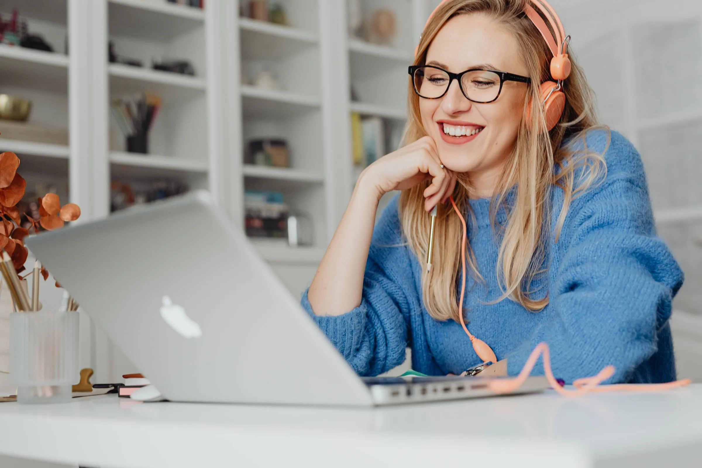 E-learning: a smiling woman with headphones at a laptop
