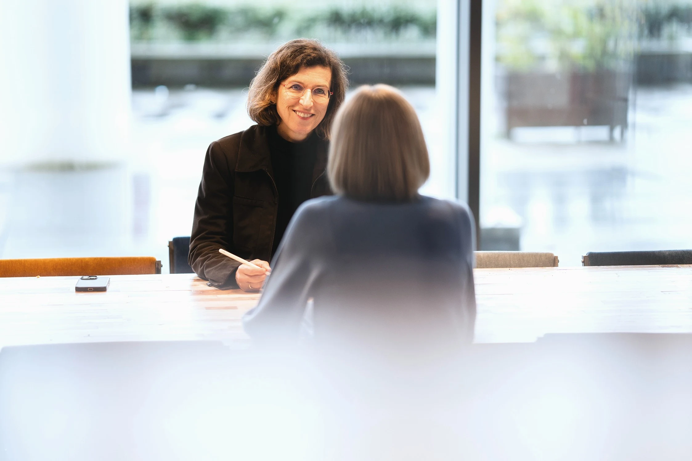 A performance advisor in conversation across a table, diagnosing a request before deciding on training.